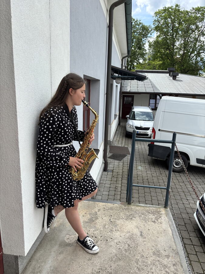Saxofonistka před budovou školy